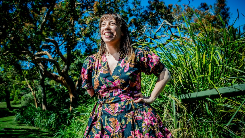Photograph of Elizabeth Wright wearing a dress and laughing, against a backdrop of green flora.